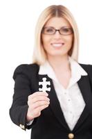 The main element. Confident mature businesswoman showing a puzzle element and smiling while standing isolated on white photo