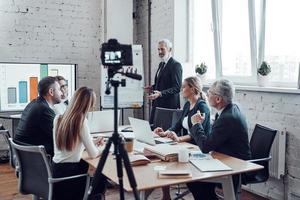 Successful business team listen a man which conducting presentation while filming staff meeting in the board room photo