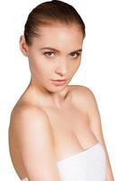 Fresh and beautiful. Top view of beautiful young woman wrapped in towel looking at camera while standing isolated on white background photo