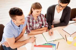 Students studying. Top view of three confident students studying while sitting at the desk together photo