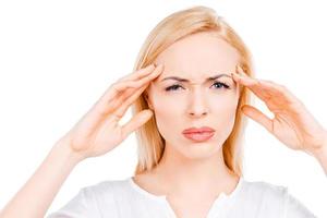 Terrible headache. Depressed mature women touching her cheekbone and looking at camera while standing against white background photo