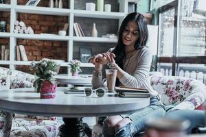 Beauty in cafe. Attractive young smiling woman checking the time while sitting in restaurant photo