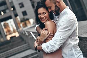 Love is in the air. Handsome young man embracing his beautiful girlfriend while spending time together in the city photo