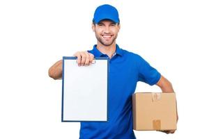 Copy space on his clipboard. Cheerful young courier stretching out clipboard and smiling while standing against white background photo