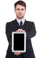 Copy space on his tablet. Confident young man in formalwear showing his digital tablet while standing isolated on white photo