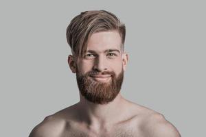 Smiling handsome. Portrait of handsome man looking at camera and smiling while standing against grey background photo