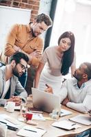 concentrado en el trabajo. grupo de jóvenes empresarios discutiendo algo en la oficina foto