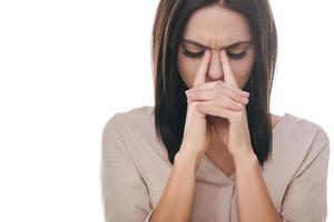 Feeling tired and stressed. Frustrated young woman massaging her nose and keeping eyes closed while standing against white background photo