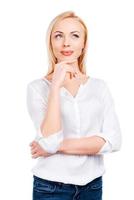 Looking for inspiration. Thoughtful mature women holding hand on chin while standing against white background photo