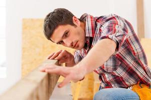 nivel de comprobación. confiado joven manitas trabajando con madera en el taller foto