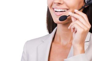 How may I help you Close-up of beautiful young businesswoman adjusting her headset and smiling while isolated on white background photo