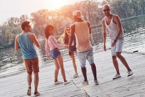 Totally carefree. Full length of young people in casual wear smiling and having fun while standing on the pier photo