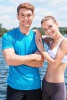 pareja de fitness. hermosa pareja joven en ropa deportiva de pie juntos al aire libre y sonriendo foto