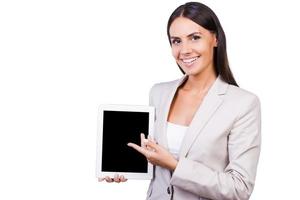 Copy space on her tablet. Beautiful young businesswoman in suit holing digital tablet pointing it while standing isolated on white background photo