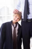 I want to be like my father. Cheerful little boy playing with necktie of his father standing near him and smiling at camera photo