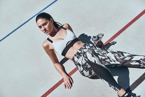 tiempo para un pequeño descanso. vista superior de una mujer joven con ropa deportiva relajándose mientras está en la pista de atletismo al aire libre foto