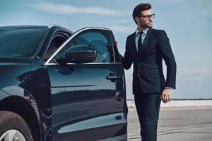 Getting ready to drive. Handsome young businessman entering his car while standing outdoors photo