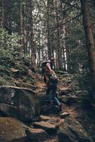 lidiando con las dificultades. toda la longitud de una pareja joven tomándose de la mano y moviéndose hacia arriba mientras caminan juntos en el bosque foto