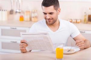 desayuno saludable. apuesto joven tomando un desayuno saludable mientras está sentado en la cocina foto