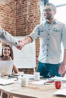 Welcome on board Two businessmen shaking hands while standing near office table photo