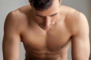 Feeling power inside. Handsome young muscular man looking down while isolated on grey background photo