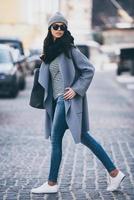 Beauty on a go. Beautiful young woman in sunglasses looking away while crossing the street photo