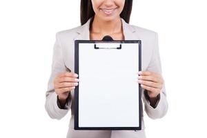 Copy space on her clipboard. Businesswoman demonstrating empty paper on a clipboard while standing against white background photo