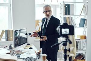 Senior man in elegant business suit sharing his business experience while making social media video photo