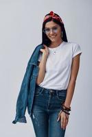 Attractive young woman in bandana carrying denim shirt on shoulder and smiling photo