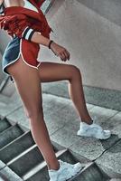 Perfect legs. Close-up of young woman in sport clothing posing on the stairs outdoors photo