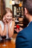 propuesta perfecta. vista trasera de un joven apuesto que hace una propuesta mientras le da un anillo de compromiso a su novia en el restaurante foto