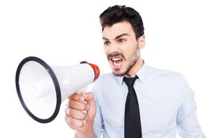 Listen to me Furious young man in shirt and tie holding megaphone and shouting while standing against white background photo