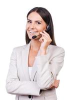 siempre dispuesto a ayudarte. hermosa joven empresaria ajustando sus auriculares y sonriendo mientras está aislada de fondo blanco foto