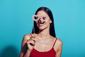 Attractive young woman looking at camera and smiling while standing against blue background photo