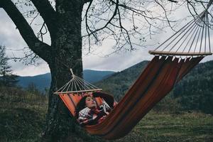 Resting after long day hiking.  Beautiful young woman lying in hammock while relaxing on the valley under the tree photo