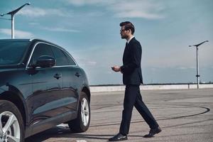 Modern businessman. Full length of handsome young businessman walking to his car photo