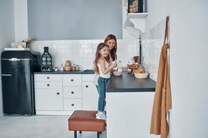 madre e hija sonriendo mientras preparan algo en la cocina foto