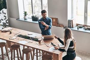 compartiendo nuevas ideas. vista superior de los jóvenes colegas que trabajan mientras pasan tiempo en el espacio de trabajo creativo foto