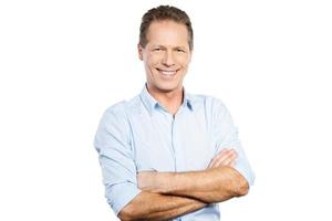 Confident and successful man. Happy young man in shirt looking at camera and keeping arms crossed while standing against white background photo