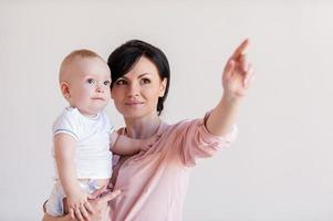 Look over there Beautiful young mother holding baby and pointing away photo