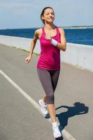 Energy inside her. Full length of beautiful young woman running along the road and smiling photo