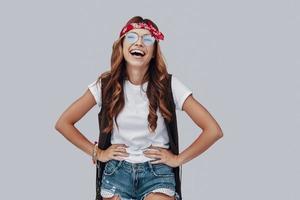 Attractive stylish young woman laughing while standing against grey background photo