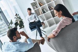 Helping others. Young married couple talking while sitting on the therapy session with psychologist photo