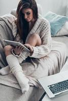 Beauty at home. Attractive young woman using digital tablet while sitting on couch at home photo