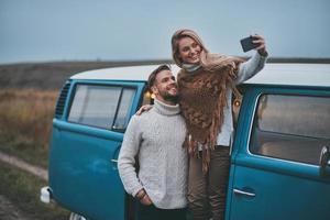 éste va en el marco. hermosa pareja joven tomando selfie y sonriendo mientras disfruta de su viaje por carretera foto