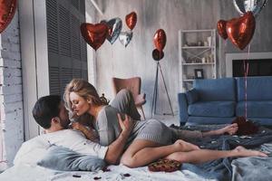 So passionate.  Beautiful young couple embracing while lying on the bed at home photo