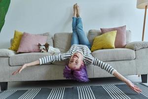 Cheerful teenage girl relaxing on the couch while little dog lying near her photo
