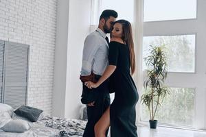 no hay reglas para ellos. hermosa joven desnudando a su novio mientras está de pie en el dormitorio foto