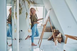 Full length of attractive young woman painting in art studio photo