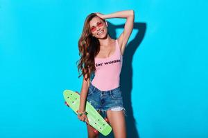 Totally carefree. Attractive young woman smiling and looking at camera while standing against blue background photo